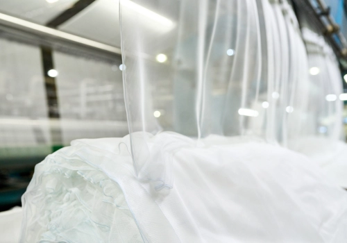 Layers of white netting fabric rolling off a machine at a manufacturing facility