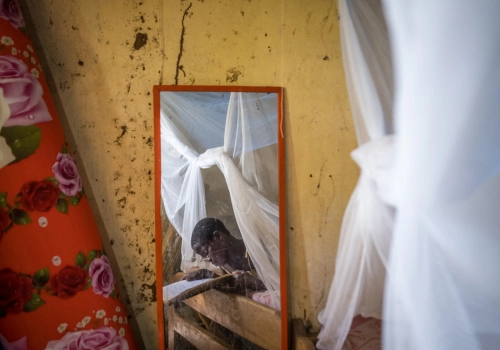 A young child in Uganda reading under a PermaNet 3.0 mosquito net