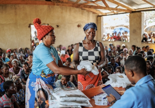 Two women picking up a bed net from a distribution
