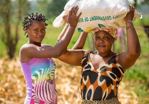 Two women in a field with a bag of grain